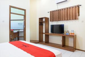 a bedroom with a bed and a television on a desk at RedDoorz near Baluran National Park in Pandean