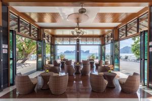 Phi Phi Long Beach Resort & Villa-SHA Extra Plus في جزيرة في في: غرفة بها كراسي وطاولات وأبواب زجاجية