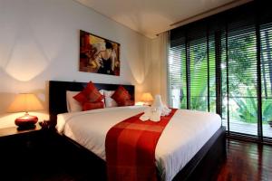 a bedroom with a bed with a red and white blanket at Kata Gardens 2 bedroom near beach in Kata Beach