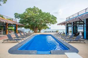 Phi Phi Long Beach Resort & Villa-SHA Extra Plus في جزيرة في في: مسبح وكراسي والمحيط في الخلفية