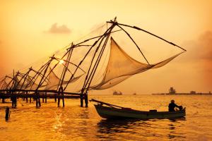 a man in a boat with a sail in the water at Goodkarma Inn in Cochin