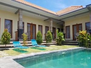 a villa with a swimming pool and two chairs at Cantika Guest House in Uluwatu
