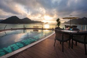 um deque com uma piscina e uma mesa com um guarda-sol em Stellar of the Seas Cruise em Ha Long