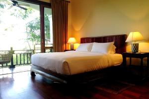 a bedroom with a bed and a balcony at Villa Albizia in Chiang Mai in Doi Saket