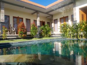 a villa with a swimming pool in front of a house at Cantika Guest House in Uluwatu +8 photos