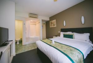 um quarto com uma cama grande e uma televisão de ecrã plano em Hotel Northbridge em Perth
