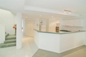 a white kitchen with a counter and a staircase at Bayside Beauty in Busselton