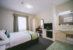 a hotel room with a bed and a tv at Hotel Northbridge in Perth