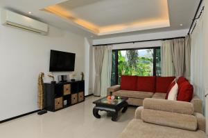 a living room with a couch and a tv at Thaimond Residence by TropicLook in Nai Harn Beach