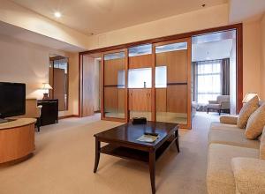 Dalian Asia Pacific Service Apartment (Former Somerset Harbour Court Dalian) في داليان: غرفة معيشة مع أريكة وطاولة قهوة