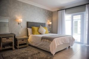 a bedroom with a bed with yellow pillows and a mirror at The Whale on Main B&B in Hermanus