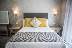 a bedroom with a bed with yellow pillows and two tables at The Whale on Main B&B in Hermanus