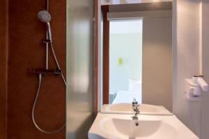 a bathroom with a shower and a white sink at The Originals Access, Hôtel Figeac in Figeac