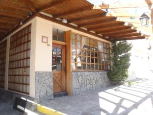 a house with a wooden door and a stone wall at Hotel Cottbus in San Carlos de Bariloche
