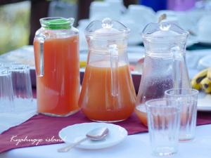 a table with three glass jars of orange juice at Lake Bunyonyi Eco Resort in Chabahinga