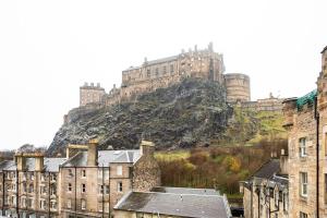 a castle on top of a hill with buildings at ALTIDO Classic 2BR Apartment with Castle Views in Old Town in Edinburgh