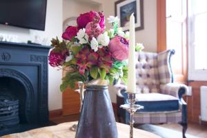 a vase of flowers on a table with two candles at ALTIDO Classic 2BR Apartment with Castle Views in Old Town in Edinburgh