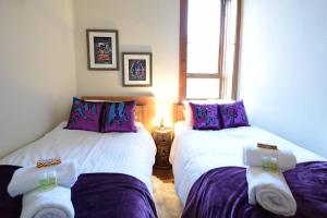2 łóżka w pokoju z fioletowo-białą pościelą w obiekcie ALTIDO Classic 2BR Apartment with Castle Views in Old Town w Edynburgu