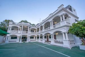 uma grande mansão branca com um jardim verde em Happiness Guesthouse em Pak Chong