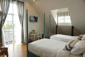 1 Schlafzimmer mit 2 Betten, einem Tisch und einem Fenster in der Unterkunft Nai Suan Bed and Breakfast in Chiang Rai