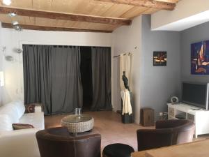 a living room with a couch and chairs and a tv at La Maison des Arts in Gordes