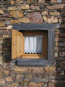 una ventana en una pared de piedra con una cortina en Quinta dos Baldo, en Freixo de Espada à Cinta