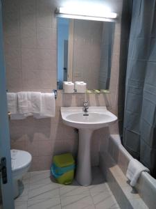 a bathroom with a sink and a toilet and a mirror at Hostal Ancla Dorada in Vigo