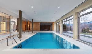 a swimming pool in a house with large windows at Wellness Hotel Říčky in Říčky