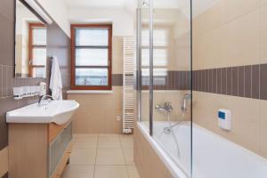 
a bathroom with a sink, mirror, and tub at Wellness hotel Říčky in Říčky
