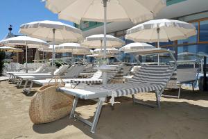 un montón de sillas y sombrillas en una playa en Hotel Gradara, en Bellaria-Igea Marina