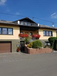 a house with a fence and flowers in front of it at Eifelflair in Retterath