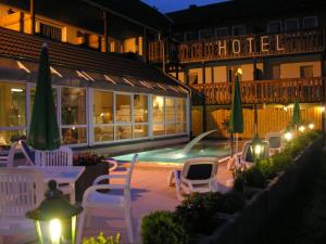 ein Hotel mit Stühlen und einem Swimmingpool in der Nacht in der Unterkunft Akzent Hotel Kaltenbach in Triberg