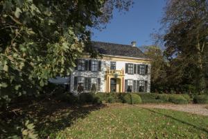 ein weißes Haus mit schwarzen Fenstern und einem Hof in der Unterkunft Hotel Landgoed Ekenstein in Appingedam