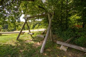 a swing set in a field with a tree at Holiday Home Juričko with private Sauna in Bizeljsko