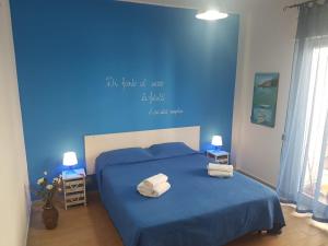 Un dormitorio azul con una cama con toallas. en Casa Vacanze Trinacria en Isola delle Femmine