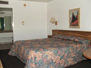 a hotel room with a bed and a table at Arizona Inn in Kingman