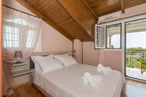 a bedroom with a bed with white sheets and a window at Villa Ismini in Zakynthos Town