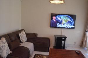 sala de estar con sofá y TV de pantalla plana en MYSECONDHOME en Harare