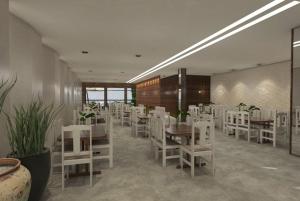 a dining room with white tables and white chairs at Marge Hotel in Aparecida