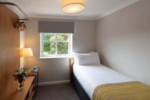 um pequeno quarto com uma cama e uma janela em PREMIER SUITES Reading em Reading