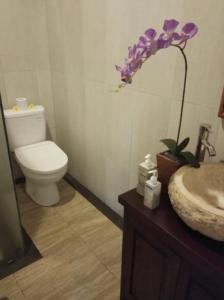 a bathroom with a toilet and a sink and a flower at Ketut Kasta Guest House in Ubud