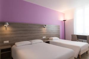two beds in a room with a purple wall at The Originals City, Hôtel Nevers Centre Gare (Inter-Hotel) in Nevers