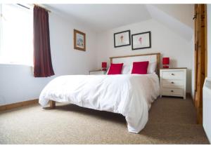a bedroom with a large white bed with red pillows at Abbey Place Net Loft in Mousehole