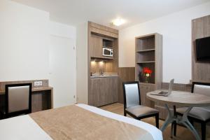 a hotel room with a bed and a table and chairs at Séjours & Affaires Reims Clairmarais in Reims