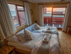 a bedroom with two beds and a large window at Island Cottage Guesthouse in Lüderitz