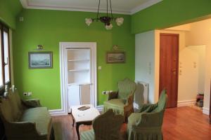 a living room with green walls and chairs and a table at Acropolis Apartment in Athens