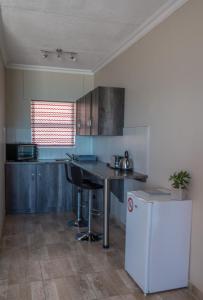 a kitchen with a counter and a table and a refrigerator at Island Cottage Guesthouse in Lüderitz
