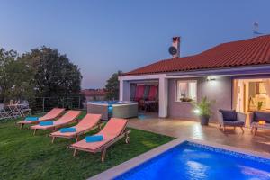 podwórko z basenem, krzesłami i domem w obiekcie Modern Villa di Rovigno with Pool, Hot Tub and Sea View w mieście Rovinjsko Selo