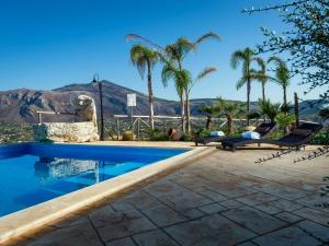 une piscine avec des palmiers et une montagne en arrière-plan dans l'établissement Belvilla by OYO Villa Le Muse, à Scopello