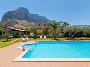 a swimming pool with a house and mountains in the background at Belvilla by OYO Carta Dieci in Cinisi